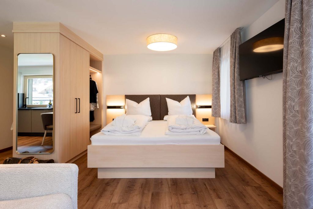 Helles Schlafzimmer mit Doppelbett und TV